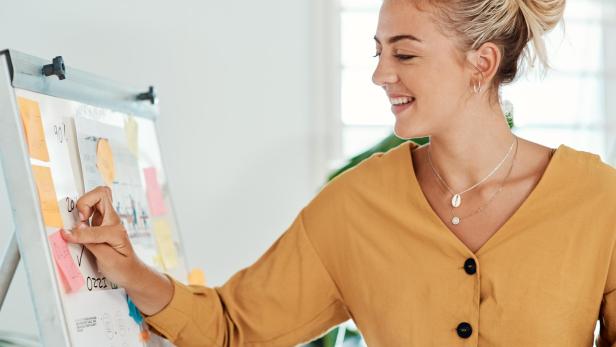 Eine junge Frau plant auf einem Visionboard