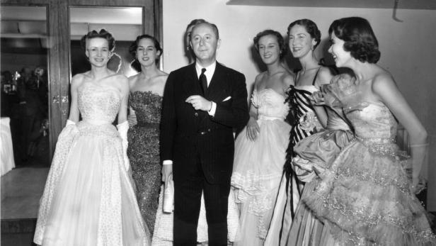 Christian Dior mit sechs Models in seinen eleganten Abendroben im Jahr 1950.