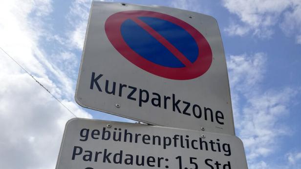 Mehrere Schilder weisen auf eine gebührenpflichtige Kurzparkzone hin; ein Pandabär ist auf dem Pfosten abgebildet.