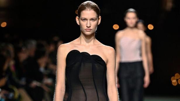 Ein Model mit einem schwarzen, schulterfreien Kleid von Victoria Beckham.