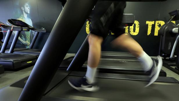 Ein Mann trainiert auf einem Laufband in einem Fitnessstudio.