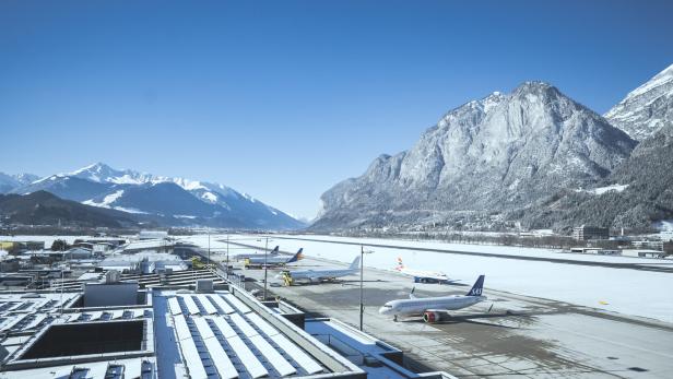 Der Flughafen Innsbruck im Winter mit schneebedeckten Bergen im Hintergrund.