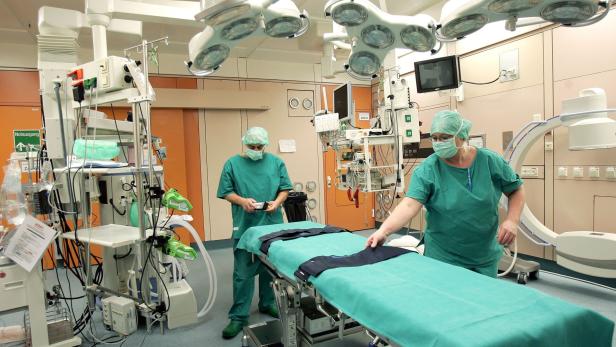 Ein Drittel von Kindern nach medikamentöser Therapie doch noch operiert Zwei Ärzte in grüner OP-Kleidung bereiten einen Operationstisch in einem hell erleuchteten Operationssaal vor.