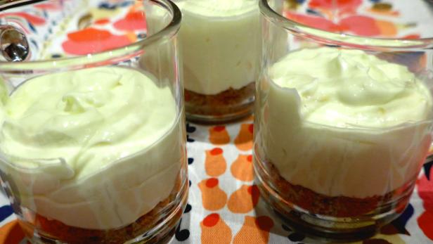 Drei Gläser mit Schichtdessert stehen auf einem gemusterten Tuch.