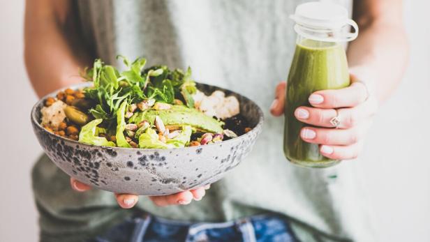 Eine gesunde Bowl mit Hülsenfrüchten, Nüssen und Salat und ein Vitamin-C-Smoothie.