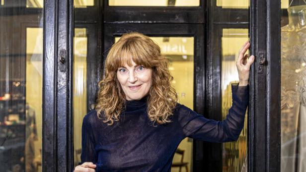 Michaela Mayer hält ein Schild mit der Aufschrift „Come in, we are open“.