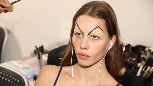 Ein Model mit ungewöhnlichem Augenbrauen-Make-up backstage bei der Mailänder Fashion Week 2025.