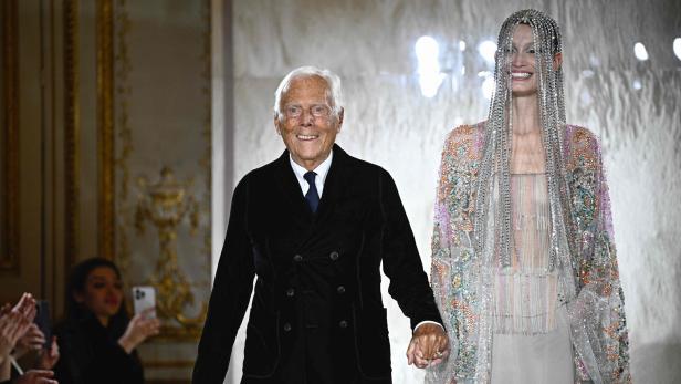 Giorgio Armani führt ein Model mit einem verzierten Kleid auf dem Laufsteg an der Modenschau.
