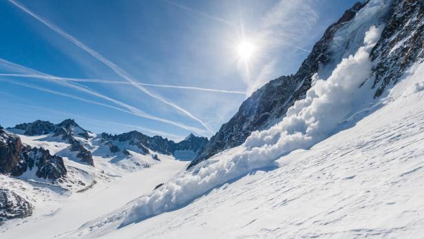 Eine Lawine geht einen schneebedeckten Berghang hinunter.