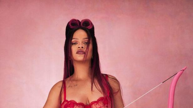 Rihanna posiert mit Pfeil und Bogen vor einem rosa Hintergrund.