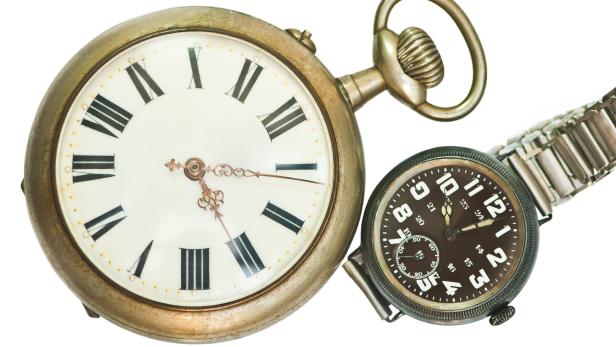 Eine goldene Taschenuhr und eine Armbanduhr liegen nebeneinander.