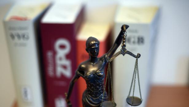 Justizia-Statue vor einer Reihe von Büchern über Gesetze