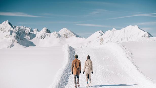 Ein Paar wandert im Winter in einer verschneiten Berglandschaft.