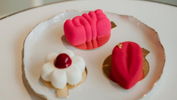 Drei farbenfrohe, moderne Petit Fours auf einem weißen Teller.