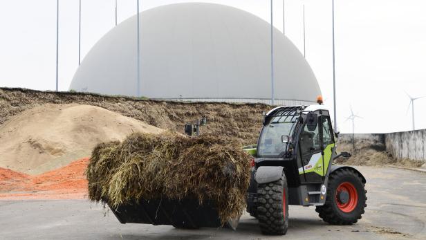 Ein Claas Scorpion Teleskoplader mit einer vollen Schaufel vor einer Biogasanlage.