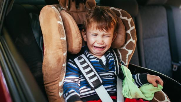 Crying baby boy in a safety car seat