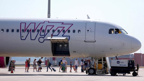 Passagiere am Rollfeld neben einem Flugzeug von Wizz Air