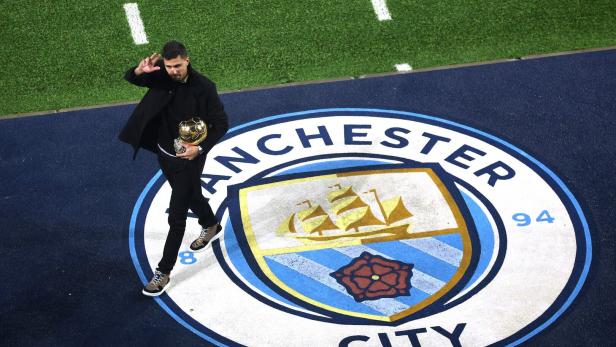 Ein Mann mit einer goldenen Trophäe steht auf dem Manchester City-Logo.