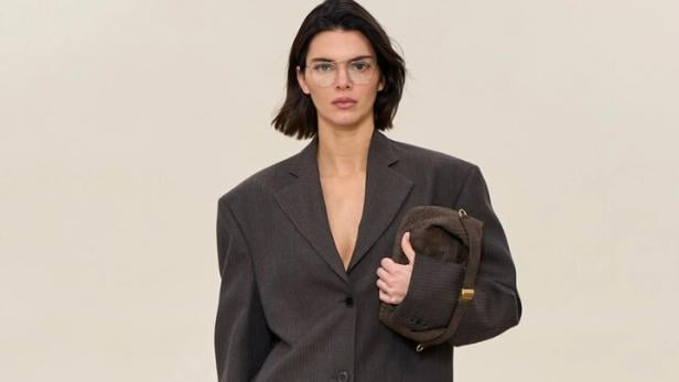 Kendall Jenner trägt einen übergroßen grauen Mantel und eine braune Handtasche auf dem Laufsteg.