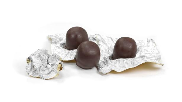 Drei Mozartkugeln liegen auf einer zerknitterten Silberfolie.