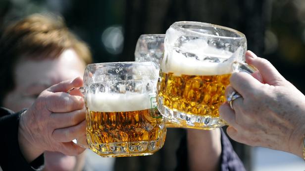 Drei Personen stoßen mit großen Bierkrügen an.