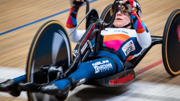 Eine Sportlerin fährt ein Handbike auf einer Radrennbahn.
