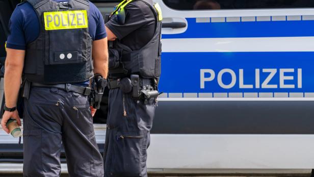 Zwei Polizisten stehen vor einem Einsatzfahrzeug.