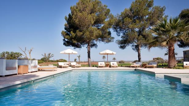 Ein Schwimmbad mit Liegestühlen und Sonnenschirmen an einem sonnigen Tag.