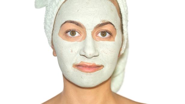 Eine Frau mit einem Handtuch auf dem Kopf und einer Gesichtsmaske.