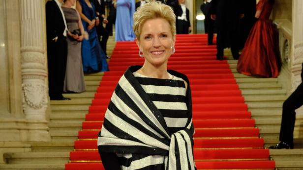 Eine Frau in einem gestreiften Kleid steht auf einer roten Treppe.