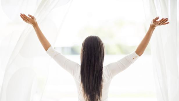Frau reißt die Fenster auf.