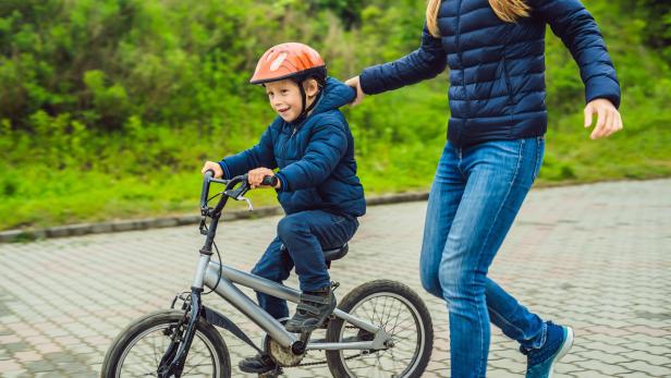 Mom teaches son to ride a bike in the park