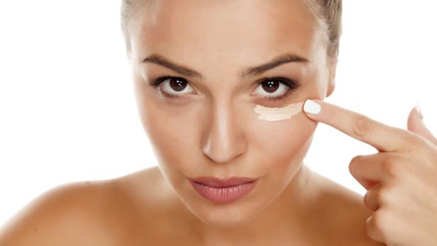 Frau trägt Concealer auf.