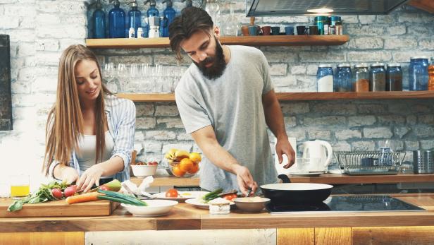 Ein Paar bereitet gemeinsam eine Mahlzeit in einer Küche zu.