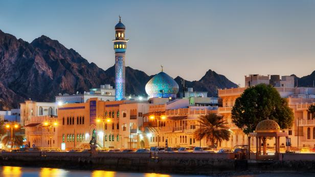 Blick auf Maskat, Oman, mit Moschee und Bergen im Hintergrund.