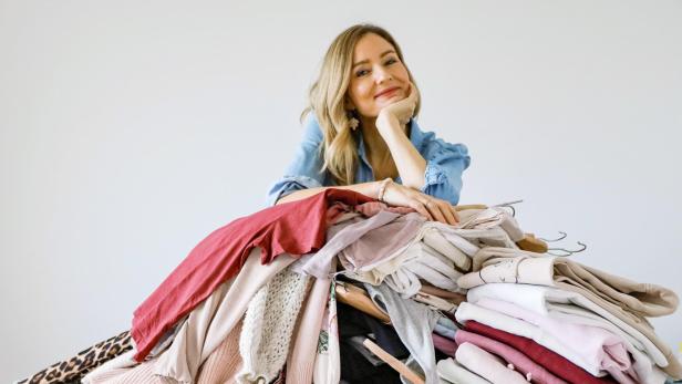 Eine Frau lehnt an einem großen Stapel Kleidung.