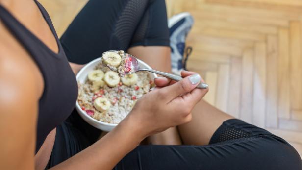 Sportlerin isst ein Proteinjoghurt mit Müsli