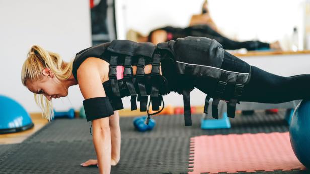 Frau beim EMS-Training: Sie trägt eine Weste, die elektrische Impulse abgibt.