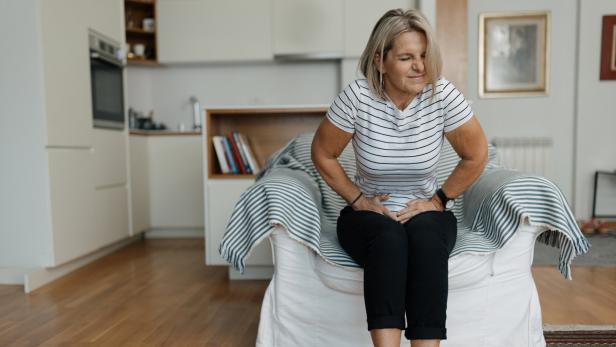 Eine Frau mit Blähungen und Magenschmerzen hält sich den Bauch.