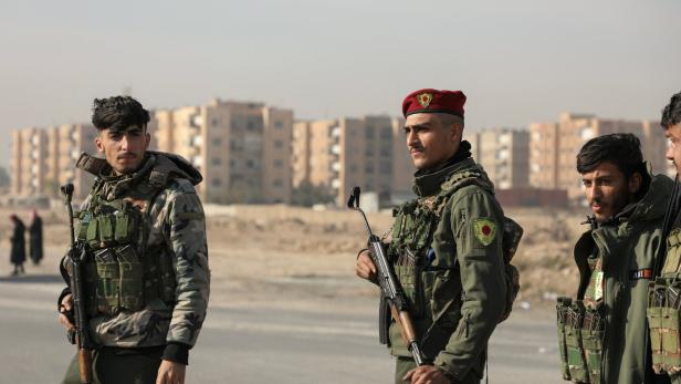 Members of Kurdish-led Syrian Democratic Forces (SDF) stand along a street, in Hasakah Symbolbild