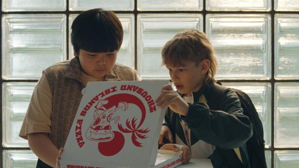 Max Zhang (li.) und Noèl Gabriel Kipp machen eine interessante Entdeckung im Pizzakarton: „Der Prank“