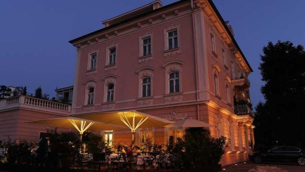 Ein rosa Gebäude mit einem beleuchteten Außenbereich am Abend.