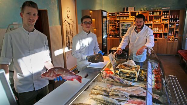 Drei Mitarbeiter präsentieren frischen Fisch in einem Geschäft namens „Lieblingsfisch“ im 2. Bezirk in Wien.