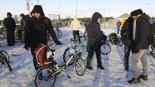 Flüchtlinge auf Fahrrädern in Nikel, auf der russischen Seite der Grenze.