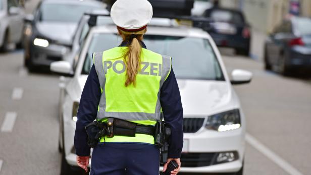 Eine Polizistin steht vor einem Streifenwagen auf der Straße.