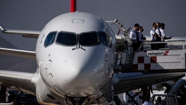 Ein Flugzeug steht am Boden, während mehrere Crewmitglieder über eine mobile Treppe einsteigen.