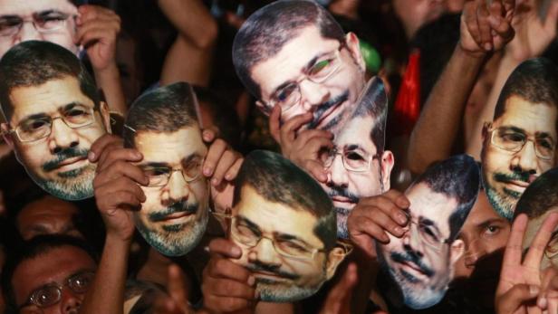 Members of the Muslim Brotherhood and supporters of deposed Egyptian President Mohamed Mursi hold up masks of him as they gather at the Rabaa Adawiya square, where they are camping, in Cairo July 12, 2013. Tens of thousands of Egyptians packed into squares and marched along streets in Cairo on Friday to protest against the military overthrow of Islamist President Mursi, and the United States called for the first time for him to be freed. REUTERS/Mohamed Abd El Ghany (EGYPT - Tags: POLITICS CIVIL UNREST TPX IMAGES OF THE DAY)