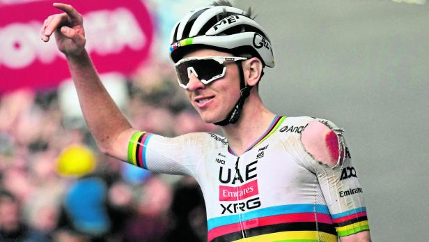 Ein Radrennfahrer in beschädigter Kleidung feiert bei einem Radrennen.