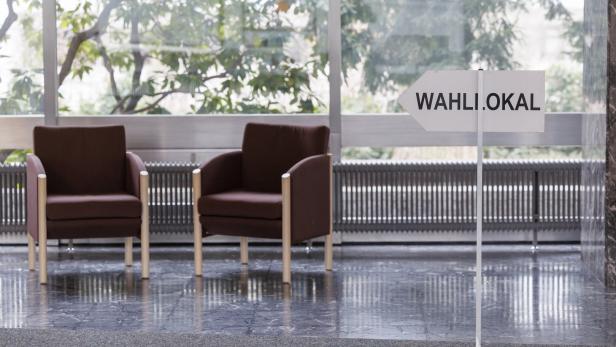 Zwei leere Sessel stehen in einem Wahllokal.