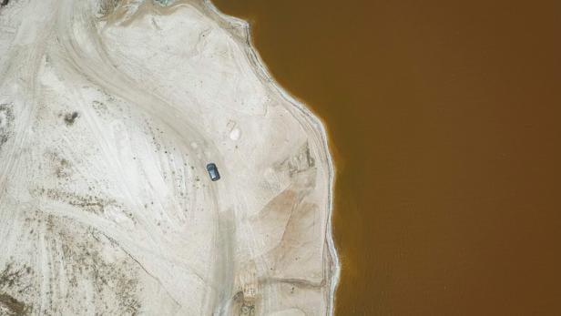 SENEGAL-ENVIRONMENT-ECONOMY-TOURISM Ein Auto steht an einem Sandstrand neben einem braunen Gewässer.